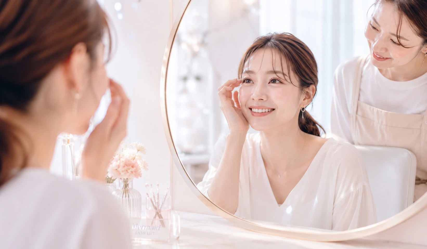 施術後、鏡で仕上がりを確認して笑顔になるお客様とアイリスト